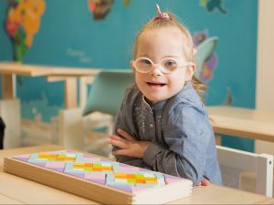 Child with Down syndrome in classroom looking to camera