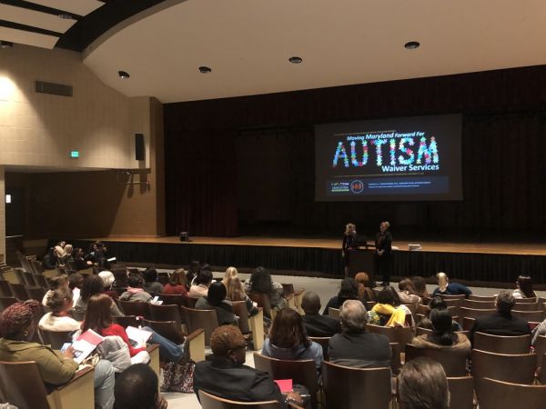 Marcella and Tiffany presenting at the Autism Waiver Services workshop in a large auditorium